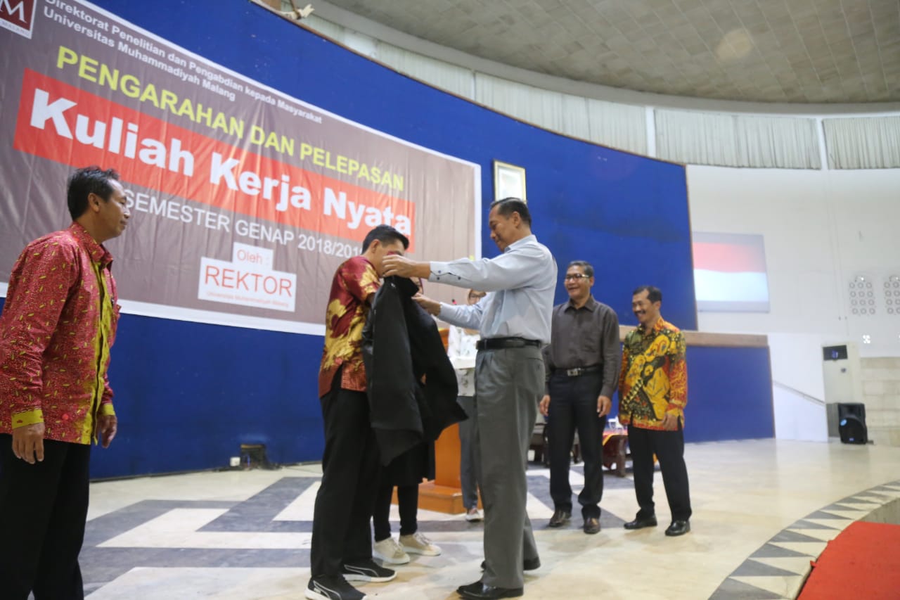 Rektor UMM Dr. Fauzan, M.Pd. menyematkan jaket KKN sebagai penanda melepas mahasiswa KKN. (Foto: 